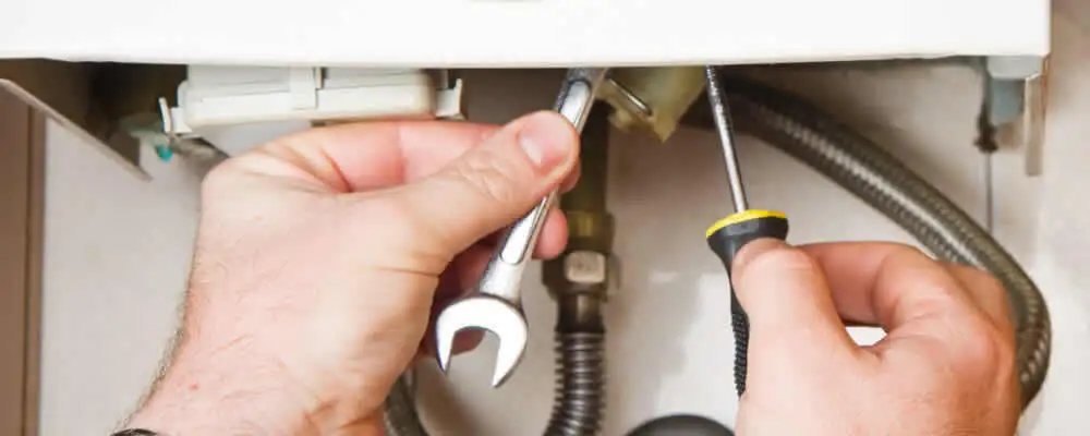 Boiler repair technician tightening pipe fittings and connections in Troy, MI