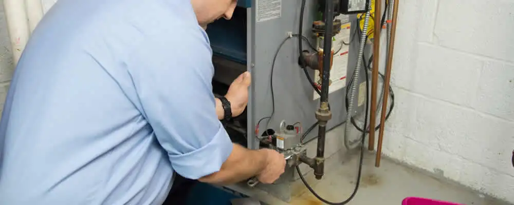 Furnace repair technician inspecting and servicing a home heating system in Troy, MI