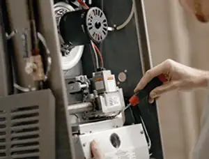 Furnace repair technician inspecting internal components and wiring in Troy, MI
