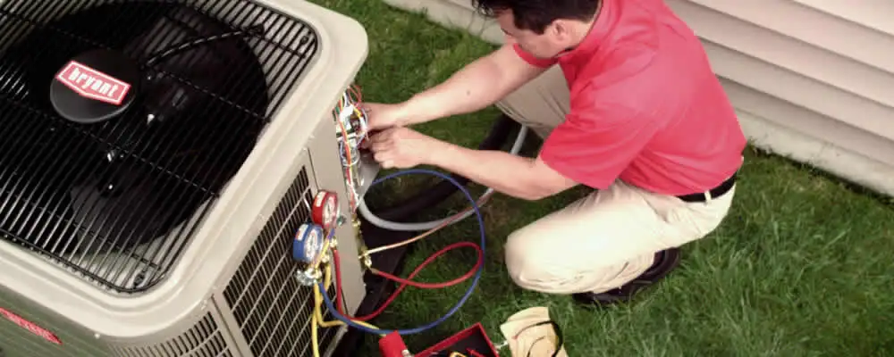 HVAC technician servicing an outdoor air conditioner unit in Troy, MI