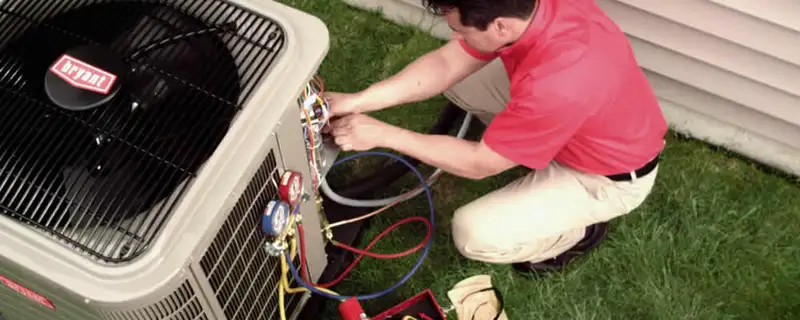 HVAC technician servicing an outdoor air conditioner unit in Troy, MI