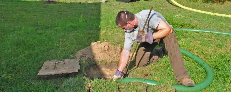 Septic pumping technician servicing a residential septic tank in Troy, MI