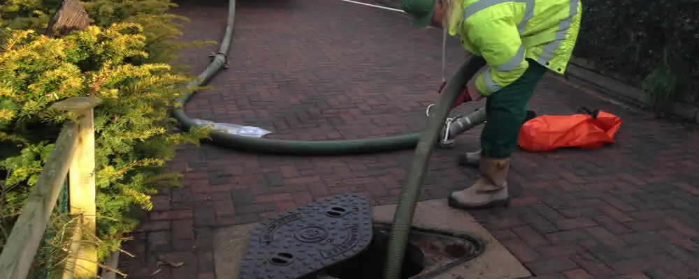 Septic tank cleaning technician servicing a septic tank with a vacuum hose in Troy, MI