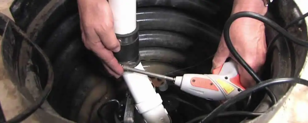 Sump pump installation technician connecting PVC discharge piping in Troy, MI
